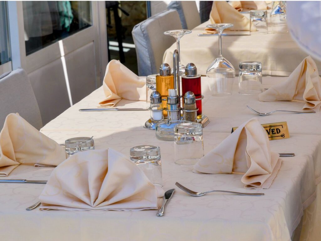 A beautifully arranged outdoor dining table with reserved sign, napkins, and condiments.