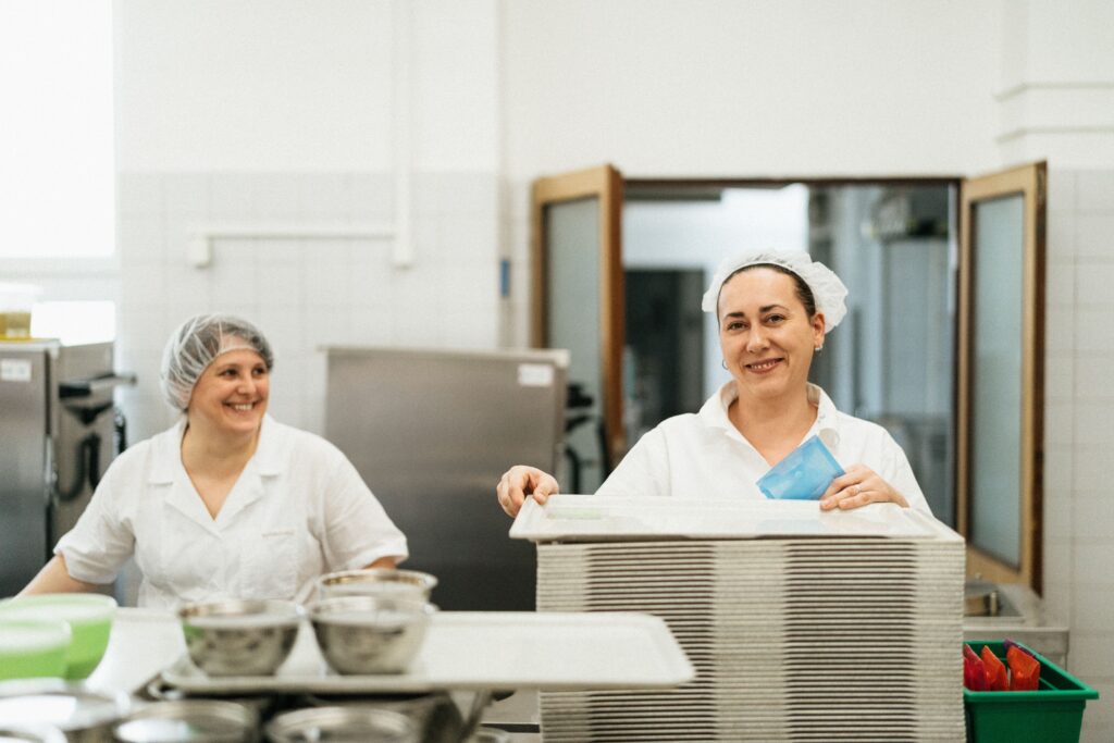 Friendly cafeteria staff working together in a kitchen, showcasing teamwork and service.